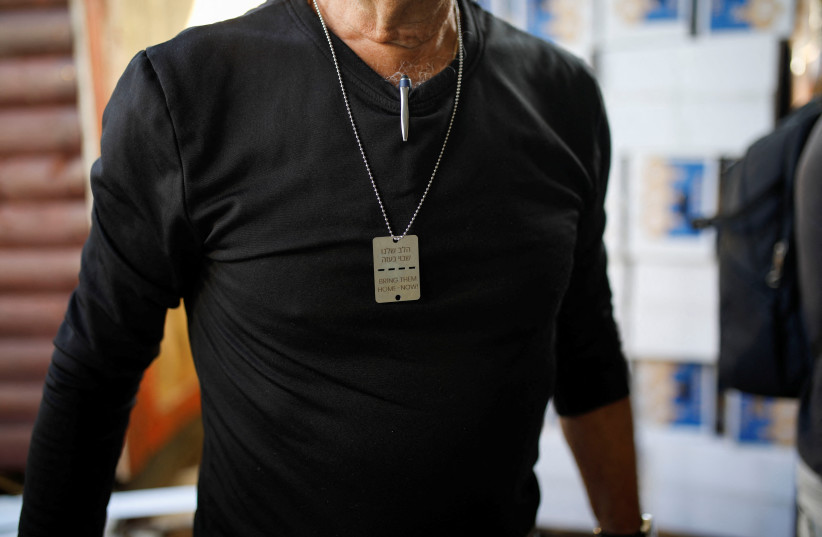A man wears a military-style dog tag calling for the return of Israeli hostages from Gaza at an agricultural farm where he has been volunteering, in Liman, close to the Lebanese border in northern Israel, January 9, 2024. The Hebrew reads ''Our hearts are held hostage in Gaza'' (credit: REUTERS/SHIR TOREM)