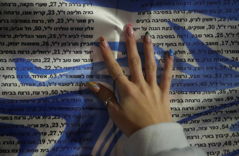 A girl puts her hand on a list of names of Israelis killed since October 7, during a 24-hour protest, in Tel Aviv, Israel, January 13, 2024 (credit: REUTERS/ALEXANDRE MENEGHINI)