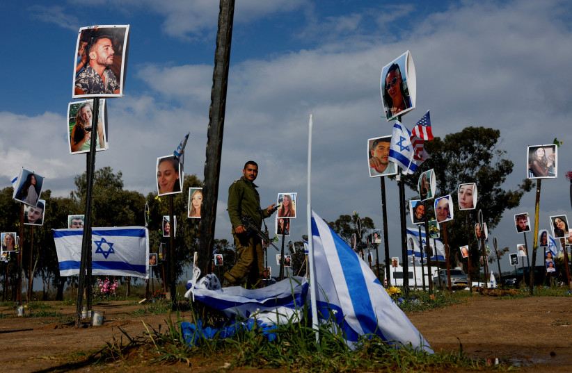  An Israeli soldier walks near pictures that are part of an installation at the site of the Nova festival, where people were murdered, raped and kidnapped during the October 7 attack by Hamas, Reim, Israel, January 14, 2024 (credit: REUTERS/TYRONE SIU)