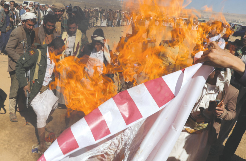  Tribal supporters of the Houthi group burn a US flag during a protest, near Sanaa, this week, against recent US-led strikes on Houthi targets. (credit: KHALED ABDULLAH/REUTERS)