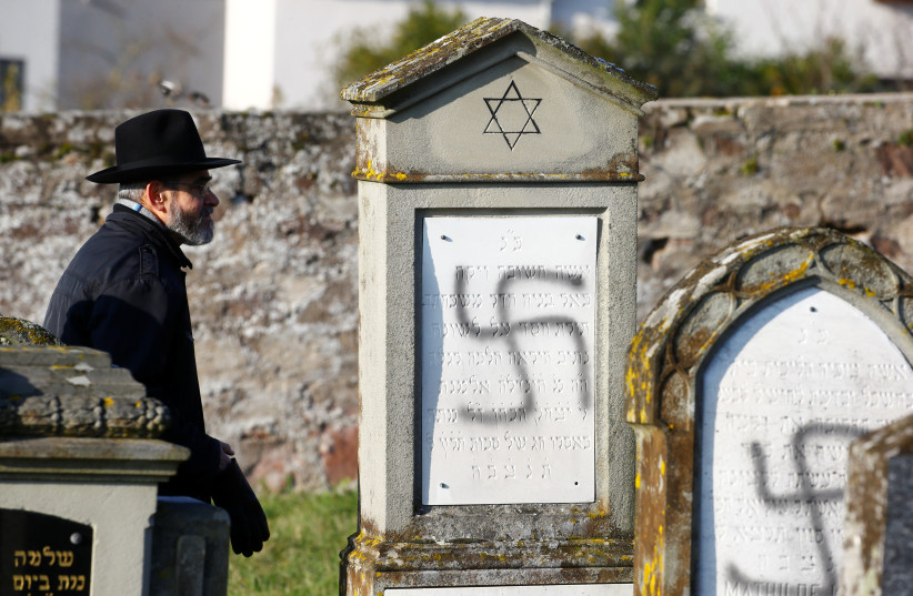  A man walks past graves desecrated with swastikas at the Jewish cemetery in Westhoffen, near Strasbourg, France, December 4, 2019.  (credit: Arnd Wiegmann/Reuters)
