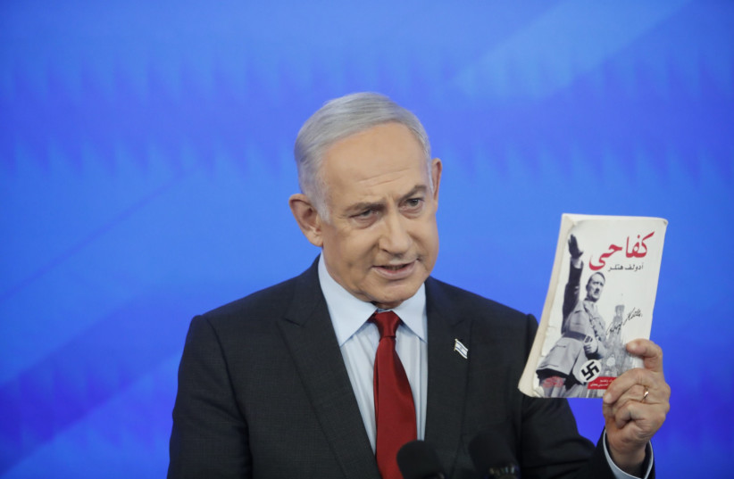 Prime Minister Benjamin Netanyahu holds an Arabic version of Adolf Hitler's Mein Kampf on January 27, 2024 (credit: TOMER APPELBAUM HAARETZ/POOL)