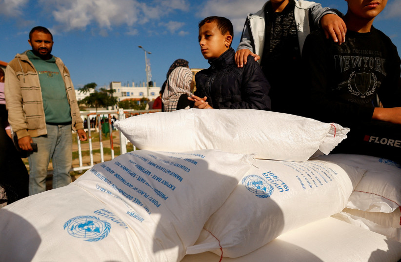Palestinians receive flour bags distributed by UNRWA in Rafah, in the southern Gaza Strip November 21, 2023. (credit: REUTERS/IBRAHEEM ABU MUSTAFA)