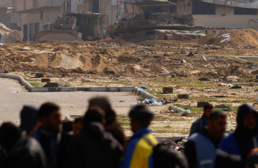 Palestinians, fleeing Khan Yunis, walk past Israeli military vehicles amid a move towards Rafah, January 30, 2024