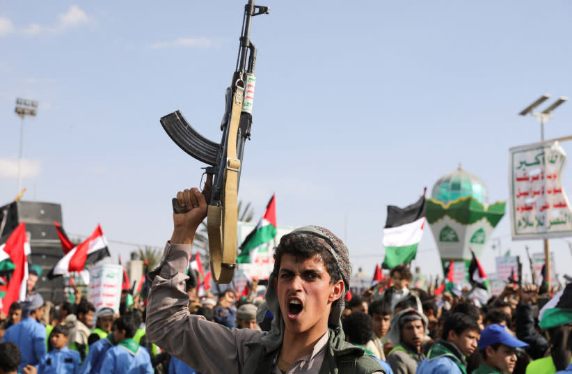  Un hombre sostiene un arma, mientras partidarios Houthi se reúnen para conmemorar diez combatientes Houthi muertos por la Marina de los EE.UU. en el Mar Rojo, en Sanaa, Yemen 5 de enero 2024. (credit: REUTERS/KHALED ABDULLAH)