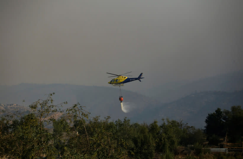  Un helicóptero que sobrevuela una zona quemada deja caer agua de un cubo para sofocar las llamas durante la propagación de los incendios forestales en Viña del Mar, Chile 3 de febrero 2024. (credit: REUTERS/SOFIA YANJARI)