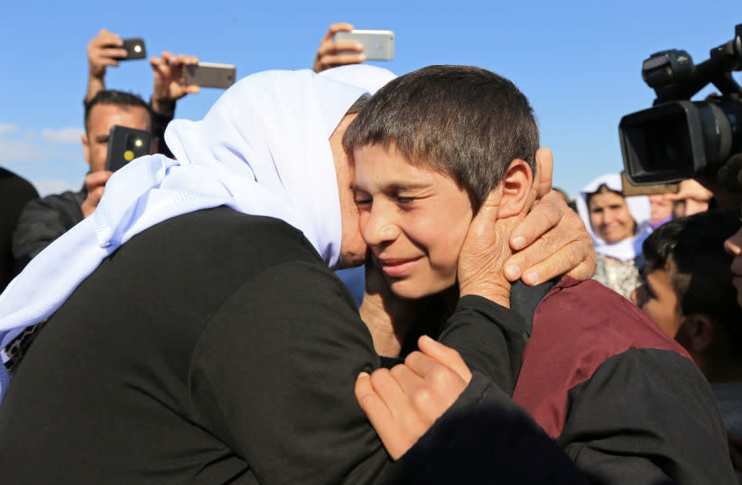  Un familiar besa a un niño sobreviviente yazidí tras su liberación de militantes del Estado Islámico en Siria, en Duhok, Irak, 2 de marzo de 2019. (credit: ARI JALAL / REUTERS)