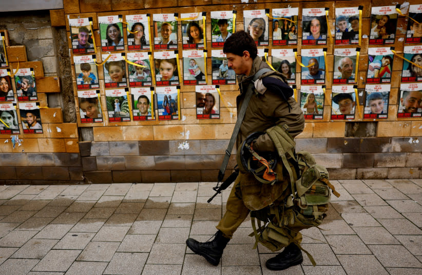  Un soldado de las FDI pasa junto a un muro con fotos de rehenes, Tel Aviv, Israel, 31 de enero de 2024. (credit: SUSANA VERA/REUTERS)