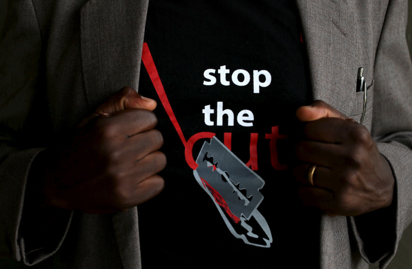  A man shows the logo of a T-shirt that reads ''Stop the Cut'' referring to Female Genital Mutilation (FGM) during a social event advocating against harmful practices such as FGM at the Imbirikani Girls High School in Imbirikani, Kenya, April 21, 2016. (credit: SIEGFRIED MODOLA/REUTERS)