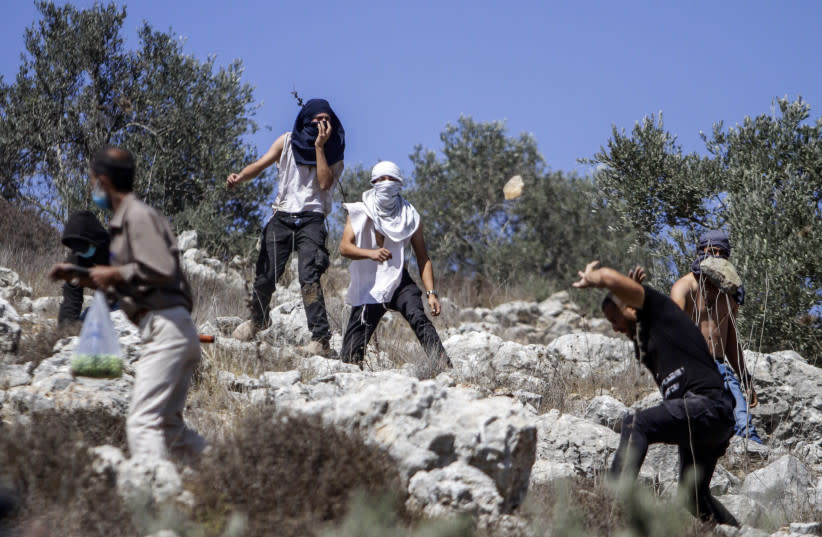  Colonos israelíes lanzan piedras contra palestinos durante la temporada anual de cosecha cerca del asentamiento israelí de Yitzhar, en Cisjordania, el 7 de octubre de 2020. (credit: NASSER ISHTAYEH/FLASH90)