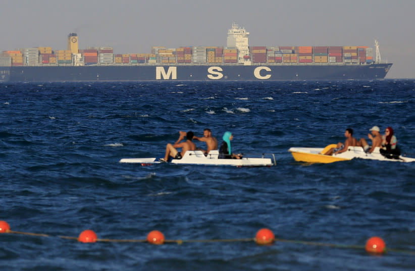  La gente disfruta del agua mientras un buque portacontenedores cruza el Golfo de Suez hacia el Mar Rojo antes de entrar en el Canal de Suez, en El Ain El Sokhna en Suez, al este de El Cairo, Egipto, 5 de septiembre de 2015. (credit: Amr Abdallah Dalsh/Reuters)