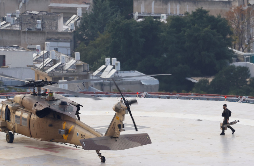  A military helicopter sits on the helipad of the Tel Aviv Sourasky Medical Center (Ichilov) as a soldier returns with an empty stretcher after dropping off an injured soldier (credit: CLODAGH KILCOYNE/REUTERS)