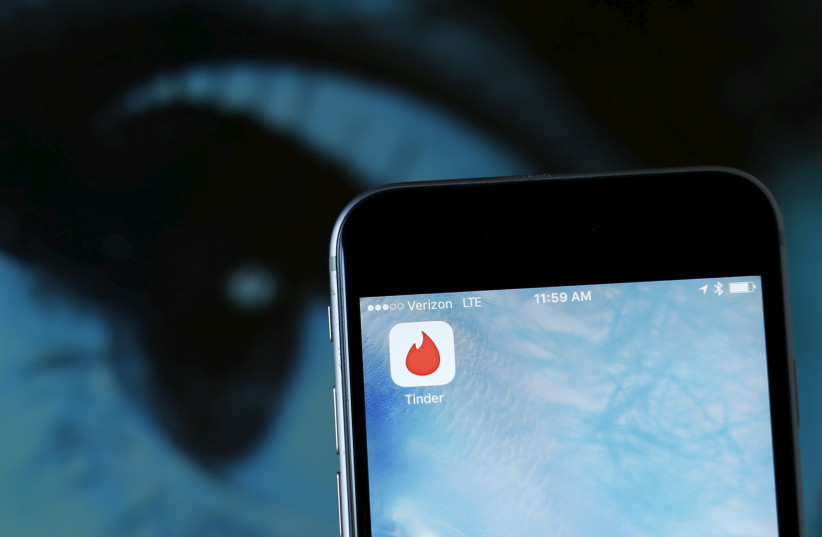  The dating app Tinder is shown on an Apple iPhone in this photo illustration (credit: MIKE BLAKE/REUTERS)