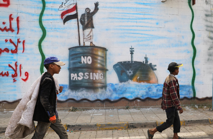  People walk past a graffiti, depicting a Houthi fighter stopping an Israeli ship off the coast of Yemen, painted on a wall of the Saudi embassy in Sanaa, Yemen February 15, 2024 (credit: REUTERS/KHALED ABDULLAH)