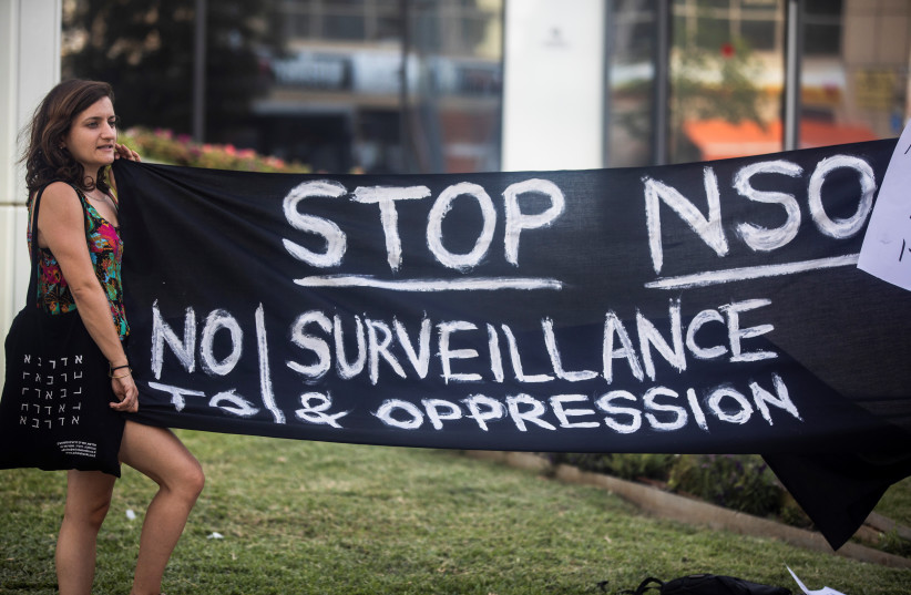  A protester holds a banner during a protest attended by about a dozen people outside the offices of the Israeli cyber firm NSO Group in Herzliya near Tel Aviv, Israel July 25, 2021 (credit: NIR ELIAS/REUTERS)
