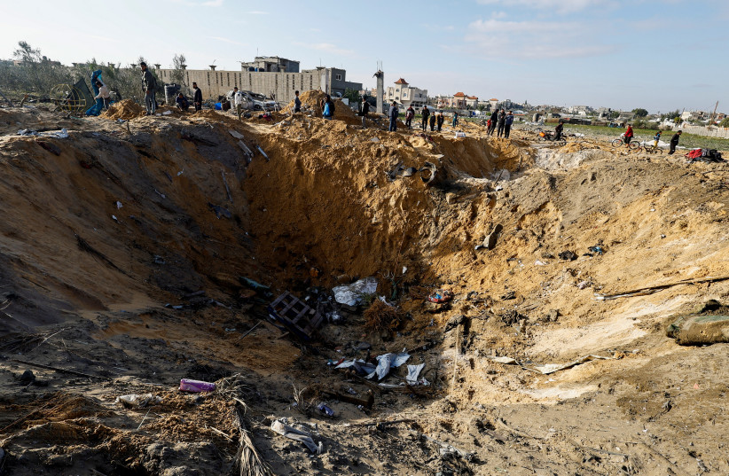 Palestinians gather near a crater at the site of an Israeli strike on a house in Rafah, in the southern Gaza Strip, February 18, 2024 (credit: REUTERS/MOHAMMED SALEM)
