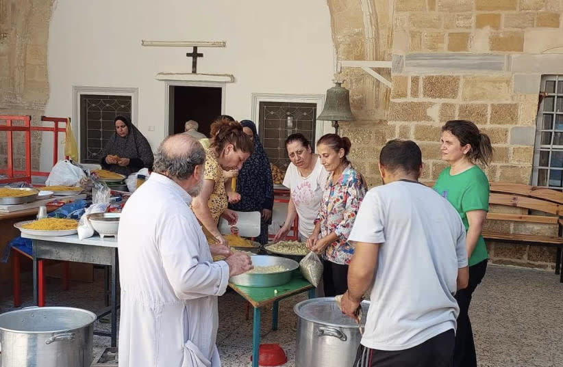  El arzobispo Alexios y un voluntario en el almacén de la iglesia de San Porfirio, donde se organizan suministros esenciales para ayudar a la vulnerable comunidad cristiana de Gaza. (credit: St. Porphyrius Greek Orthodox Church)