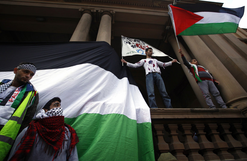  Members of the Australian Palestinian community hold banners and a flag as they stand on a balcony of the Sydney Town Hall during a protest against Israel's military action in Gaza July 20, 2014. Israel said on Sunday it had expanded its ground offensive in Gaza and militants kept up rocket fire in (credit: David Gray/Reuters)