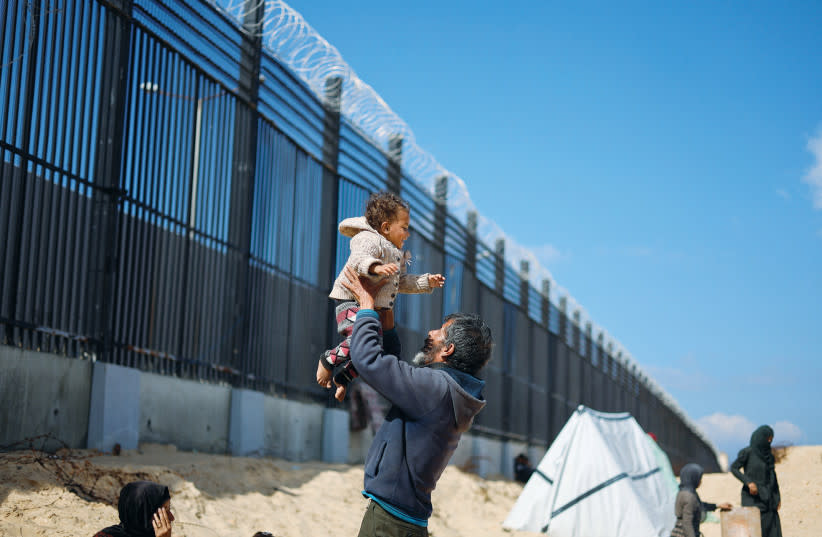  Un palestino desplazado sostiene a su nieta mientras se refugia en la frontera con Egipto, en Rafah, en el sur de la Franja de Gaza, la semana pasada. Egipto tiene una gran responsabilidad en el desarrollo de la crisis, afirma el escritor. (credit: MOHAMMED SALEM/REUTERS)