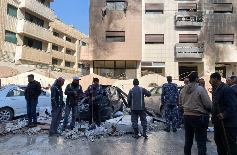  Trabajadores y personas permanecen cerca de un edificio dañado después de que, según informan los medios de comunicación estatales sirios, varios misiles israelíes alcanzaran un edificio residencial en el distrito de Kafr Sousa, Damasco, Siria 21 de febrero de 2024. (credit: REUTERS/FIRAS MAKDESI)