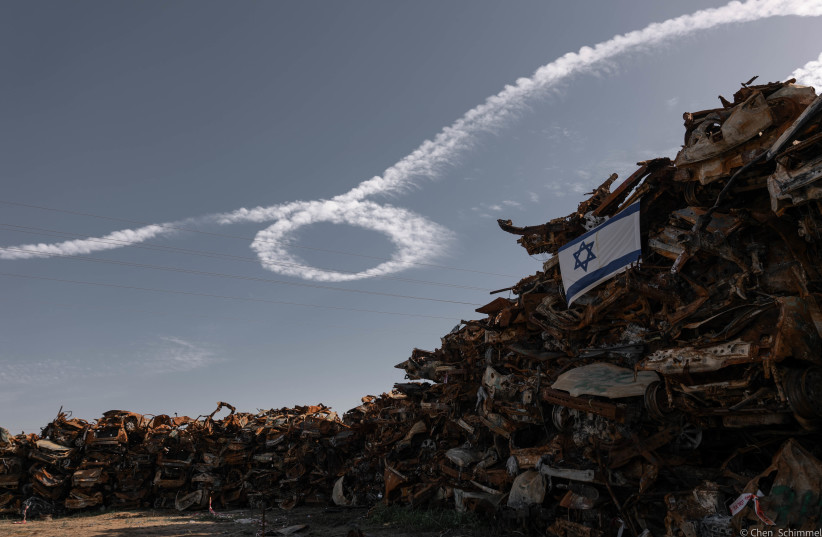  ‘RIBBONS OF Return,’ 2024. A warplane streaks across the sky above a graveyard of cars, remnants of the massacre. The plane crafts a ‘Bring them home’ ribbon in the sky.  (credit: CHEN SCHIMMEL)