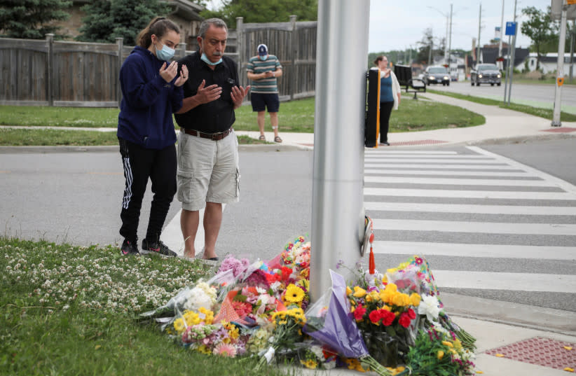 Abdullah Alzureiqi y su hija Hala rezan en el lugar donde un conductor atropelló a una familia musulmana en un presunto crimen de odio en London, Ontario, Canadá, el 7 de junio de 2021. (credit: CARLOS OSORIO/REUTERS)
