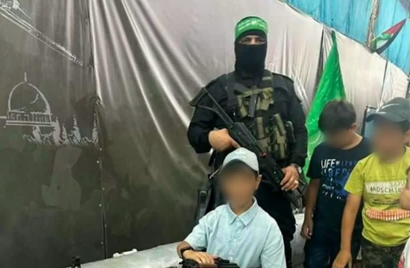  Niños de Gaza posan con armas y un terrorista de Hamás en esta foto difundida por las FDI, el 3 de enero de 2023. (credit: IDF SPOKESMAN’S UNIT)