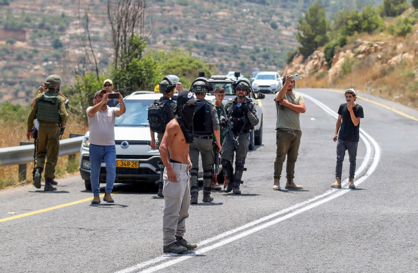  Colonos judíos miran mientras los palestinos protestan contra los asentamientos judíos en la aldea de Umm Safa, en Ramala, Cisjordania, el 7 de julio de 2023. (credit: FLASH90)