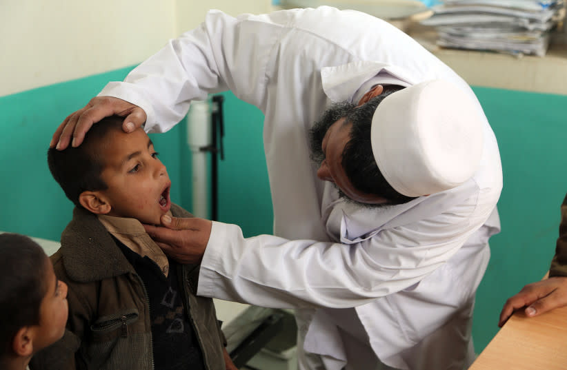  Un médico afgano revisa las amígdalas de un paciente en una clínica médica en el distrito de Sarobi, provincia de Kabul, Afganistán, 7 de diciembre de 2013. Médicos de la Combined Joint Special Operations Task Force-Afghanistan visitaron la clínica como parte de un programa de divulgación médica. (credit: PUBLIC DOMAIN)