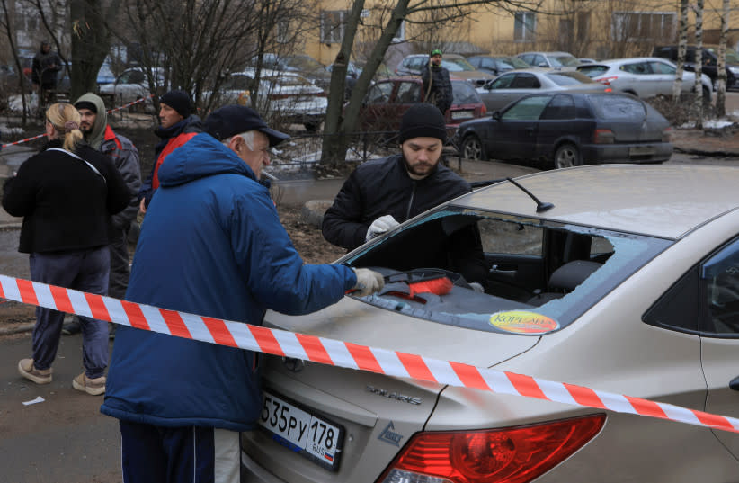   Unos hombres retiran los cristales rotos de un coche dañado tras un supuesto ataque con drones en San Petersburgo, Rusia, 2 de marzo de 2024. (credit: STRINGER/ REUTERS)