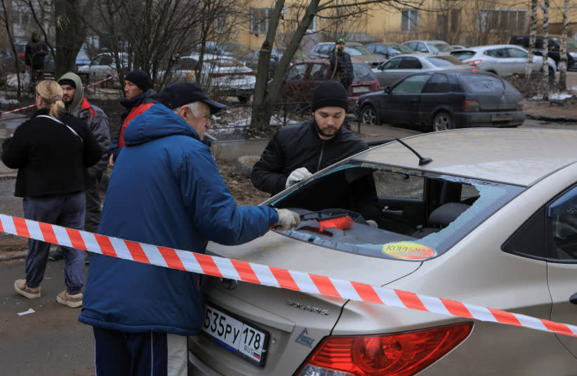 Unos hombres retiran los cristales rotos de un coche dañado tras un supuesto ataque con drones en San Petersburgo, Rusia, 2 de marzo de 2024.