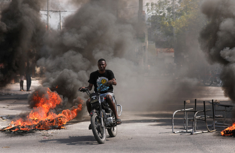  A man drives past a burning barricade during a protest against Prime Minister Ariel Henry's government and insecurity, in Port-au-Prince, Haiti March 1, 2024. (credit: REUTERS)