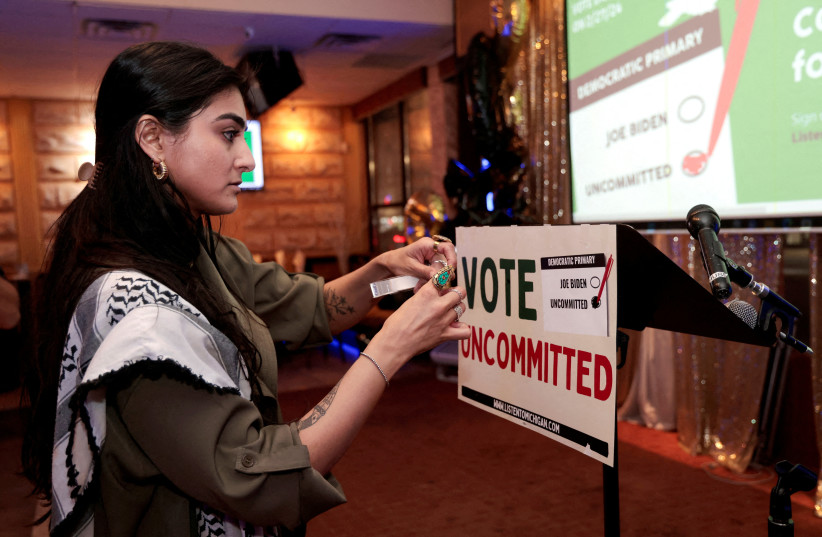 Activist Natalia Latif tapes a Vote Uncommitted sign on the speaker's podium during an uncommitted vote election night gathering as Democrats and Republicans hold their Michigan primary presidential election, in Dearborn, Michigan, US, February 27, 2024.