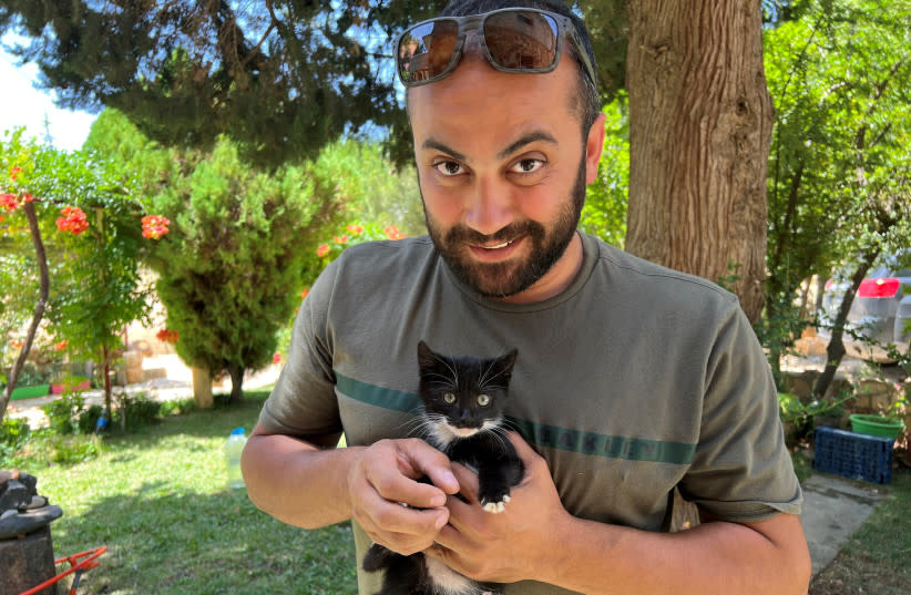  El periodista visual de Reuters Issam Abdallah sostiene un gatito mientras posa para una foto en Saaideh, Líbano, el 4 de julio de 2023. (credit: REUTERS/EMILIE MADI)