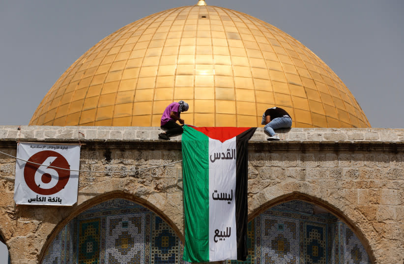  Palestinos montan una bandera nacional en una protesta el último viernes de Ramadán antes de la oración frente a la Cúpula de la Roca, en el recinto conocido por los musulmanes como Noble Santuario y por los judíos como Monte del Templo, en la Ciudad Vieja de Jerusalén el 29 de abril de 2022. (credit: AMMAR AWAD/REUTERS)