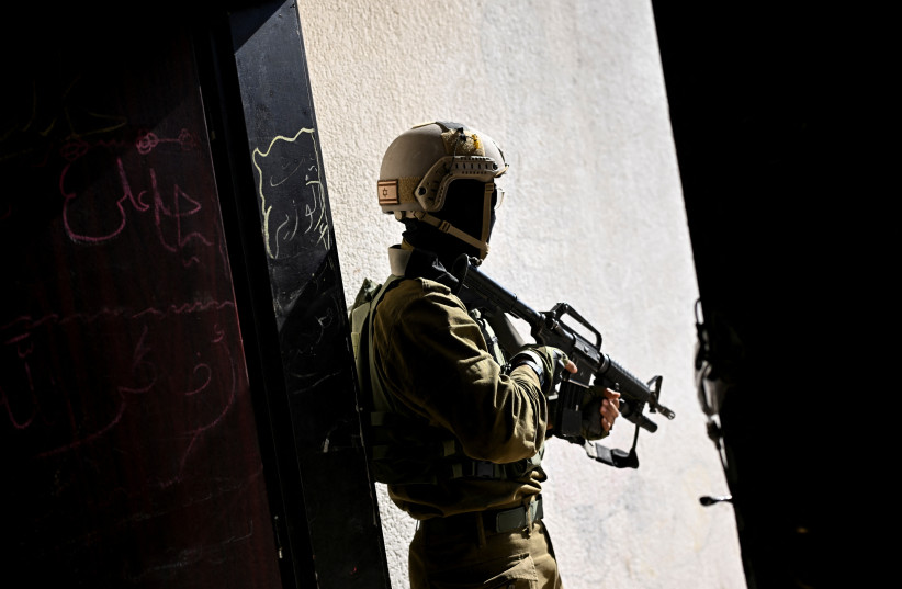  An Israeli soldier holds a gun, amid the ongoing conflict between Israel and the Palestinian Islamist group Hamas, in the Gaza Strip, February 8, 2024.  (credit: DYLAN MARTINEZ/REUTERS)