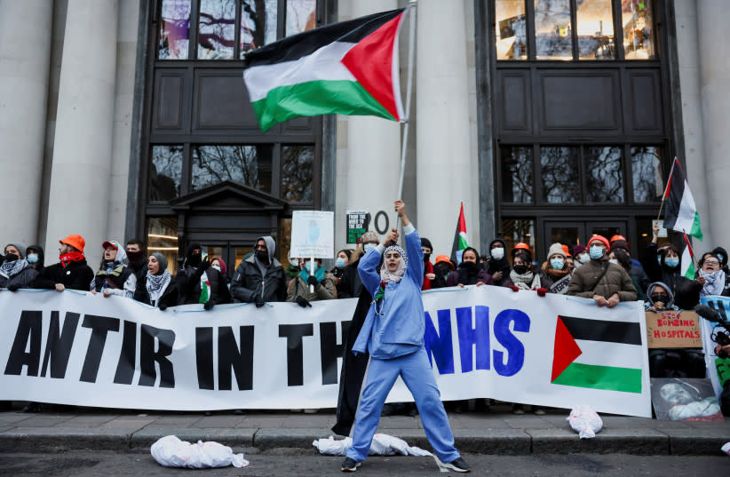  Una mujer ondea una bandera palestina mientras un piquete de ''Health Workers for a Free Palestine'' se manifiesta contra la empresa de software Palantir Technologies UK bloqueando el acceso a sus oficinas, en Londres, Gran Bretaña, el 21 de diciembre de 2023. (credit: REUTERS/Isabel Infantes)