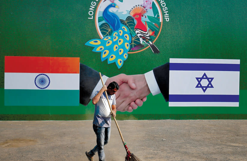  Un trabajador municipal limpia la calle frente a un cartel que muestra banderas indias e israelíes con motivo de la visita del primer ministro Netanyahu, Ahmedabad, India, enero de 2018. (credit: REUTERS/AMIT DAVE)