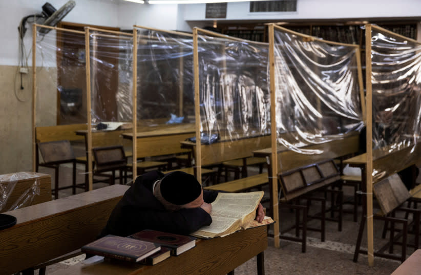 Un judío ultraortodoxo estudia en una Yeshiva, o seminario judío, equipado con mamparas para proteger contra la propagación de la enfermedad del coronavirus (COVID-19), en el barrio de Mea Shearim de Jerusalén el 2 de marzo de 2021. (credit: RONEN ZVULUN/REUTERS)