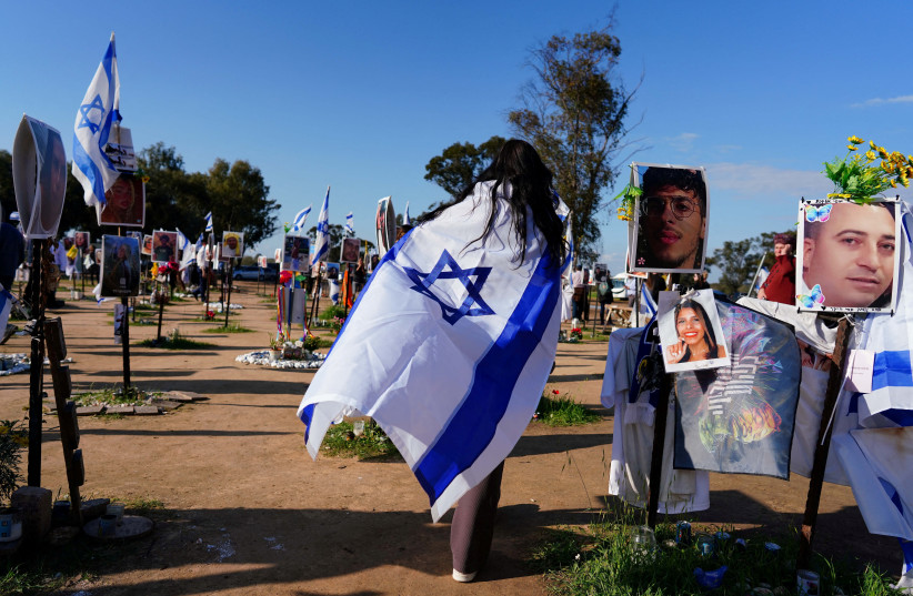  Samantha Malcar, a tourist from Canada, walks with an Israeli flag as she visits the site of the Nova festival, where people were killed and kidnapped during the October 7 attack by Hamas gunmen from Gaza, in Reim, southern Israel, January 25, 2024. (credit: ALEXANDRE MENEGHINI/REUTERS)