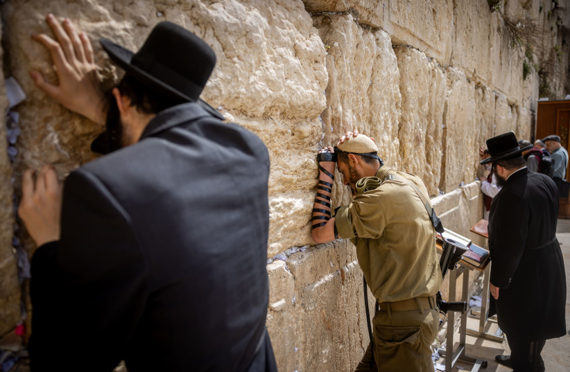  An Israeli soldier prays next to an ultra orthodox Jewish man at the Western Wall, in Jerusalem (credit: Chaim Goldberg/Flash90)