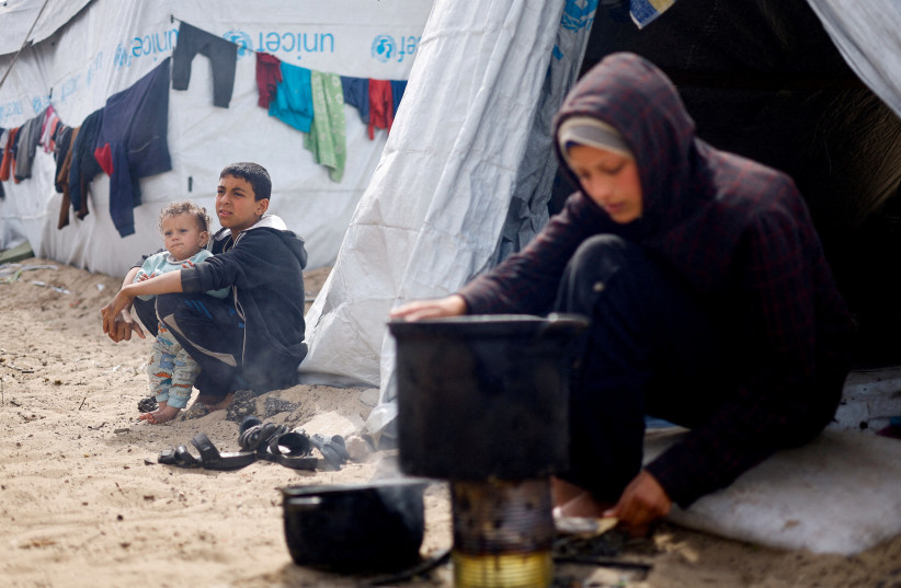  Displaced Palestinian children, who fled their houses due to Israeli strikes, sit at a tent camp, amid the ongoing conflict between Israel and the Palestinian Islamist group Hamas, in Rafah in the southern Gaza Strip, March 6, 2024. (credit: REUTERS/MOHAMMED SALEM/FILE PHOTO)