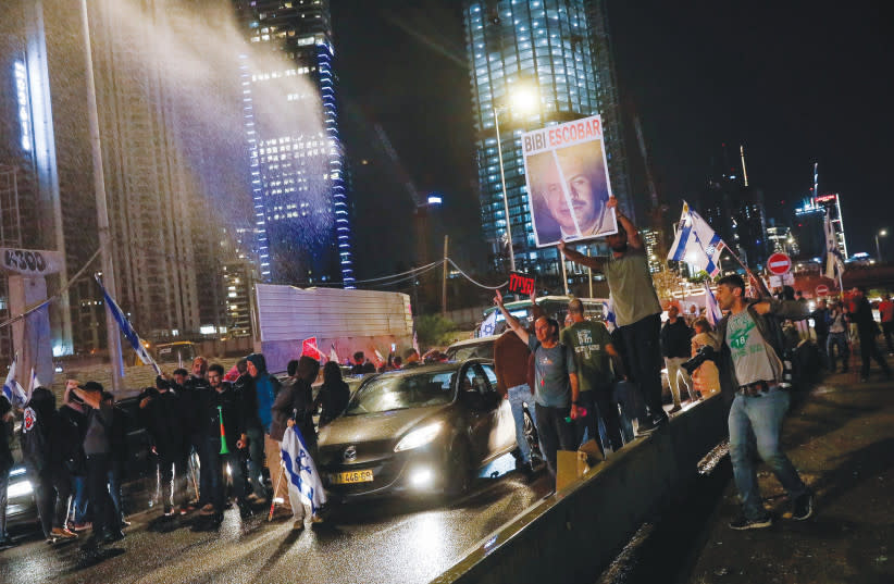  Manifestantes que bloquean la autopista Ayalon en Tel Aviv reciben el impacto del agua de un cañón durante una protesta celebrada ayer para pedir la liberación de los rehenes. (credit: MIRIAM ALSTER/FLASH90)