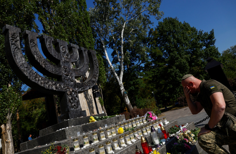  A Ukrainian serviceman prays next to a memorial for the victims of Babyn Yar (Babiy Yar), one of the biggest single massacres of Jews during the Nazi Holocaust, during a commemorative ceremony in Kyiv, Ukraine September 29, 2023.  (credit: VALENTYN OGIRENKO/REUTERS)