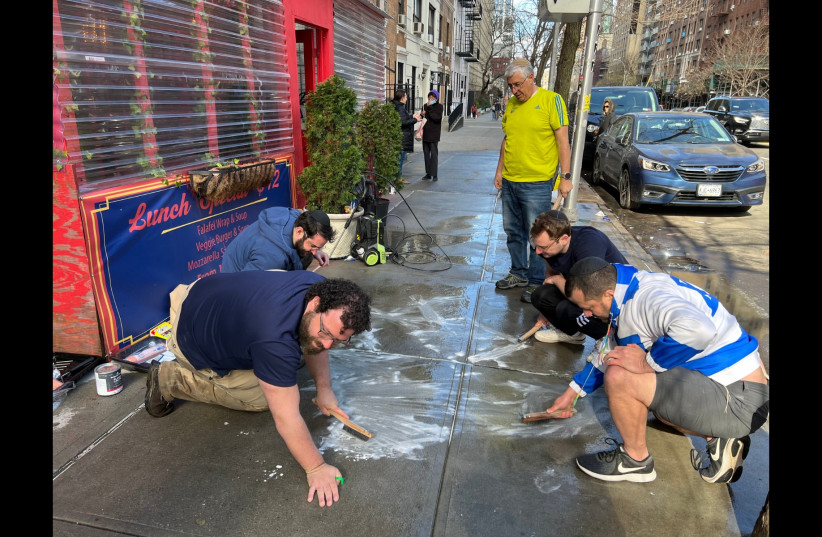 On their hands and knees, a group of Jewish volunteers scrub pro-Palestinian graffiti from the sidewalk outside of Effy's Café, a kosher restaurant on the Upper West Side. (credit: Jackie Hajdenberg)