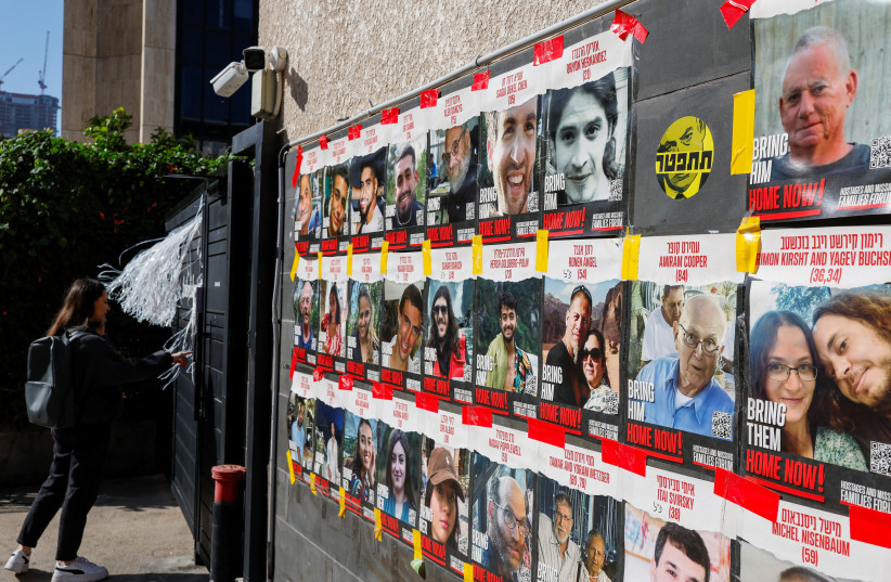  A woman stands next to posters with photos of hostages kidnapped in the deadly October 7 attack on Israel by the Palestinian Islamist group Hamas from Gaza, in Tel Aviv, Israel March 20, 2024.  (credit: CARLOS GARCIA RAWLINS/REUTERS)