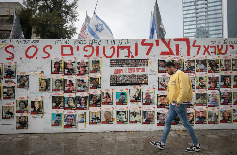  People walk by photographs of Israelis still held hostage by Hamas terrorists in Gaza, in Tel Aviv. March 19, 2024 (credit: MIRIAM ALSTER/FLASH90)