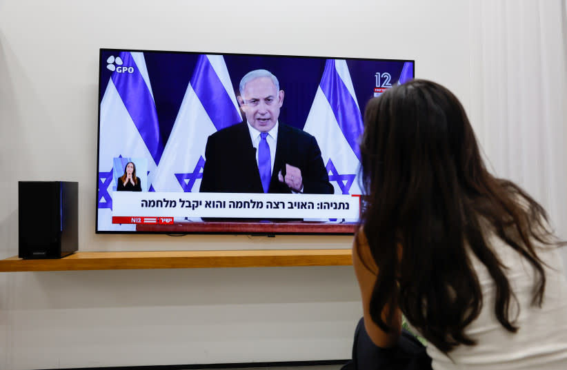  UNA MUJER observa al Primer Ministro Benjamin Netanyahu hacer una declaración al público sobre la guerra en curso. (credit: NATI SHOHAT/FLASH90)