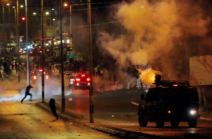  Palestinos corren mientras un vehículo militar israelí dispara botes de gas lacrimógeno durante una protesta antiisraelí por la tensión en Jerusalén, en Belén, Cisjordania 10 de mayo 2021. (credit: MUSSA QAWASMA/REUTERS)