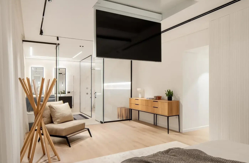   View from the bed towards the bathroom including a retractable TV from the ceiling  (credit: Yoav Peled, Studio Peled)